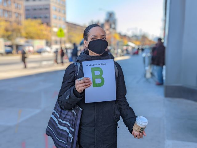 Janina Samuels of Manhattan holds up a grade for de Blasio: a letter "B".
